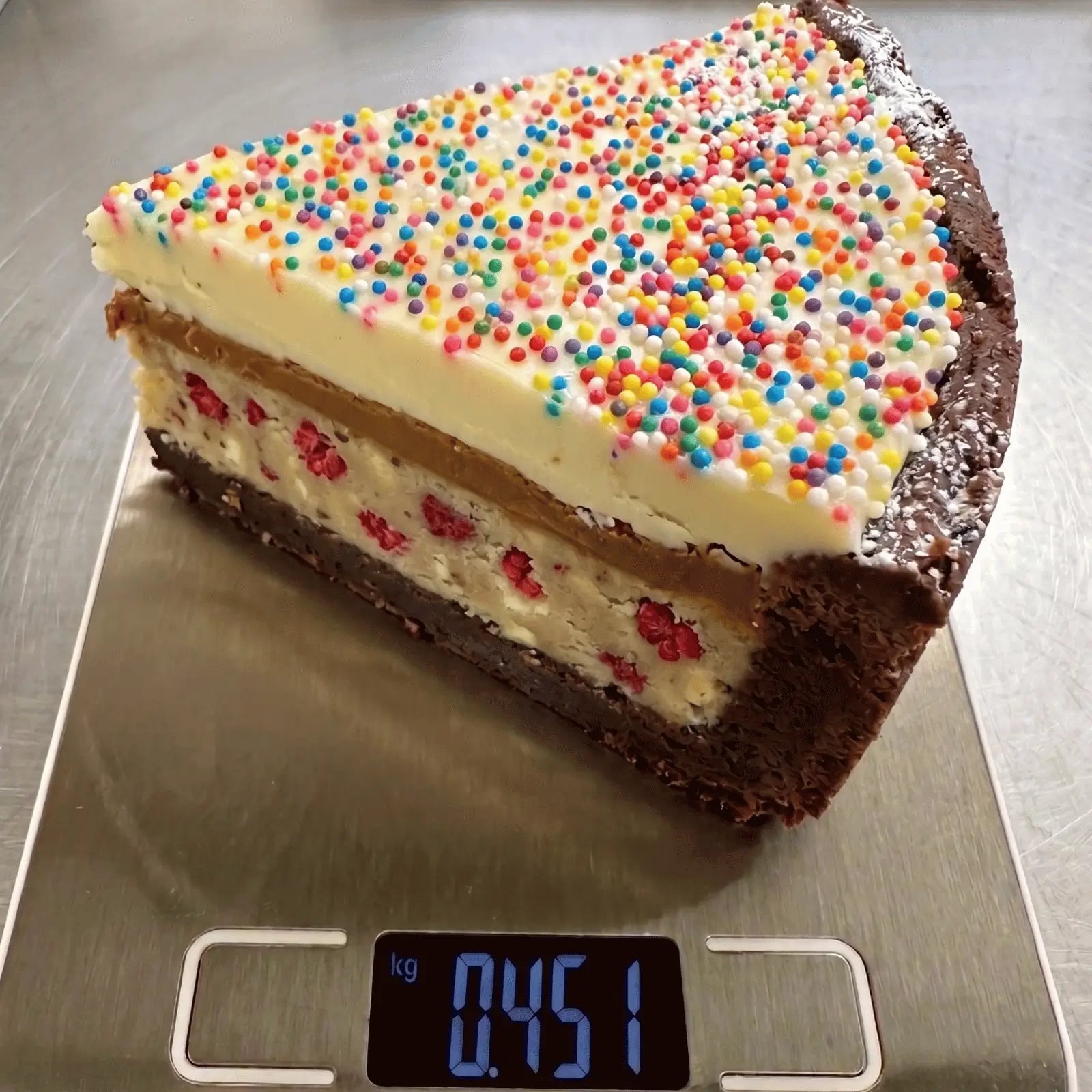 The Big Dotty Slice - layered brownie cake slice with raspberry cookie dough, Biscoff, white chocolate ganache and colourful dots